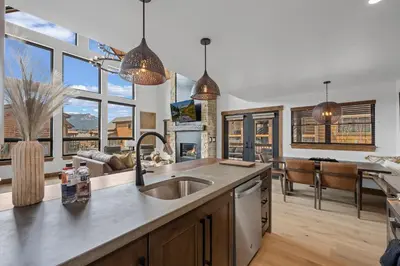 a kitchen with a sink and a living room at Brand NEW Located on Lake Estes Private Jacuzzi Two Patios Indoor and Outdoor Fireplace in Estes Park