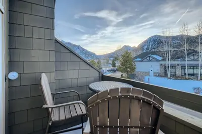 two chairs and a table on a balcony with mountains at Drake Landing #A8 condo in Frisco