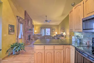 a kitchen with wooden cabinets and a living room at Charming Home with Yard about 12 Mi to Fort Collins in Loveland