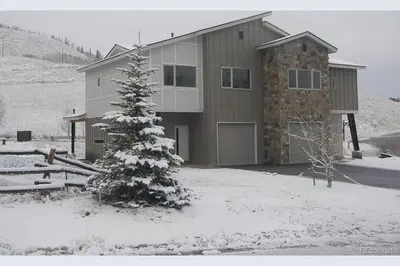 a house in the snow with a tree in front of it at 3BD/3BA- Updated Cozy Ski Retreat with Garage at the Base of Granby Ranch in Granby