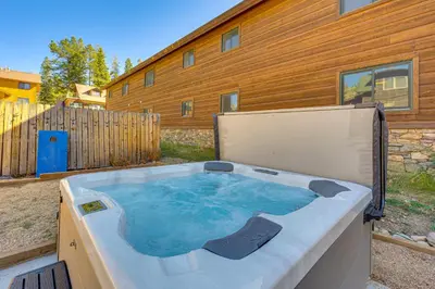 a hot tub in a yard in front of a building at Walk to Water Grand Lake Home with Hot Tub! in Grand Lake
