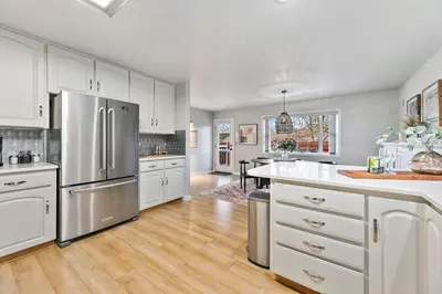 a kitchen with white cabinets and a stainless steel refrigerator at Scandinavian Chic - Hot Tub, Bikes and Lake Life! in Loveland