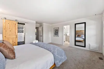 a bedroom with a large white bed and a mirror at Scandinavian Chic - Hot Tub, Bikes and Lake Life! in Loveland