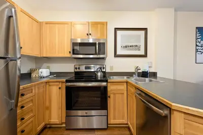 a kitchen with stainless steel appliances and wooden cabinets at Three-Bedroom Apartment in Keystone