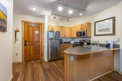a kitchen with wooden cabinets and a stainless steel refrigerator at Three-Bedroom Apartment in Keystone