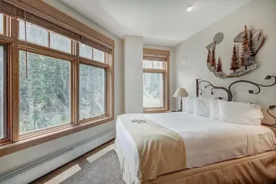 a bedroom with a large bed and two windows at Luxurious 2 BR in River Run Village with Ski in ski out, Kids Ski Free condo in Dillon