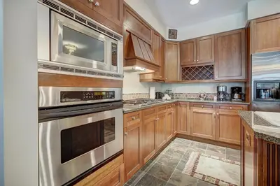 a kitchen with wooden cabinets and stainless steel appliances at Luxurious 2 BR in River Run Village with Ski in ski out, Kids Ski Free condo in Dillon