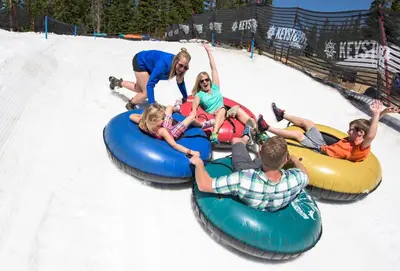 a group of people riding on tubes on a playground at Luxurious 2 BR in River Run Village with Ski in ski out, Kids Ski Free condo in Dillon