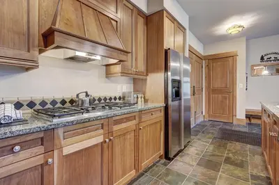 a kitchen with wooden cabinets and a stainless steel refrigerator at Luxury 3 BR in River Run Village Featuring Ski in, ski out! condo in Dillon