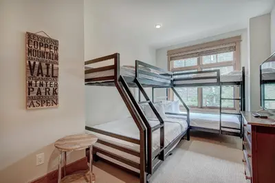 a room with three bunk beds and a stool at Luxurious 3 BR in River Run Village with Ski-In Out condo in Dillon