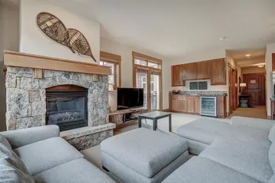 a living room with couches and a stone fireplace at Luxurious 3 BR in River Run Village with Ski-In Out condo in Dillon