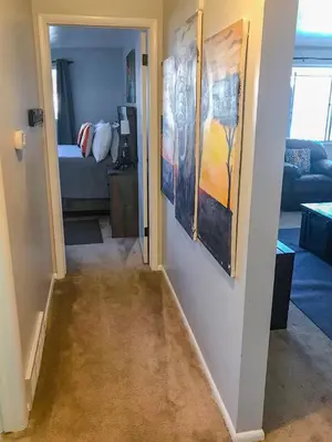 a hallway leading into a living room with paintings on the wall at Quiet Sunlit Retreat w many Travel Amenities n Grg in Lakewood