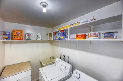a laundry room with a washing machine and shelves at Quiet Sunlit Retreat w many Travel Amenities n Grg in Lakewood