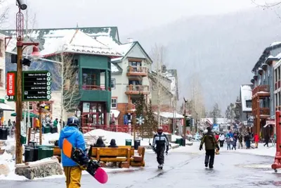 a group of people walking down a street with a snowboard at 1 Bedroom Mountain Condo In River Run Village With Expansive Mountain Views And Walking Distance To Ski Slopes in Keystone