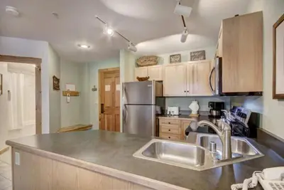 a kitchen with a sink and a stainless steel refrigerator at 1 Bedroom Mountain Condo In River Run Village With Expansive Mountain Views And Walking Distance To Ski Slopes in Keystone