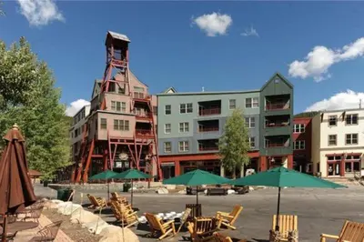 a group of chairs and umbrellas in front of a building at 1 Bedroom Mountain Condo In River Run Village With Expansive Mountain Views And Walking Distance To Ski Slopes in Keystone