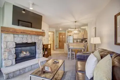 a living room with a stone fireplace and a living room at 1 Bedroom Mountain Condo In River Run Village With Expansive Mountain Views And Walking Distance To Ski Slopes in Keystone
