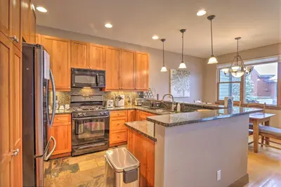 a kitchen with wooden cabinets and stainless steel appliances at 5 Mi to Breckenridge Skiing Mtn Gem with Hot Tub! in Breckenridge