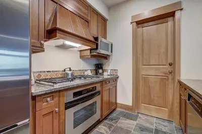 a kitchen with wooden cabinets and a stove top oven at Luxurious 1 BR in River Run Village with Ski in ski out condo in Dillon