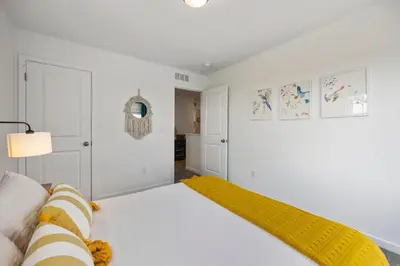 a white bedroom with a bed and a yellow blanket at Spacious Home, Great Backyard with Mtn Sunset Views! in Loveland