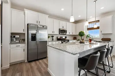 a kitchen with white cabinets and a stainless steel refrigerator at Spacious Home, Great Backyard with Mtn Sunset Views! in Loveland