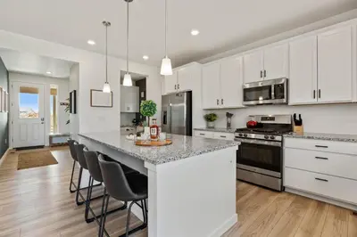 a kitchen with white cabinets and a island with bar stools at Spacious Home, Great Backyard with Mtn Sunset Views! in Loveland