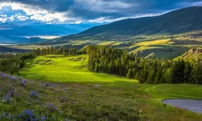 a golf course in the hills with trees and a field at Luxurious 3 BR in River Run Village Featuring Ski in, ski out condo in Dillon