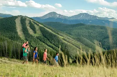 a family walking on a hill in the mountains at Luxurious 2 BR in River Run Village Featuring Ski in ski-out condo in Dillon