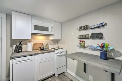 a small kitchen with a stove and a microwave at Fresh Downtown Longmont Apartment - Walk to Main! in Longmont