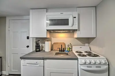a white kitchen with a sink and a microwave at Fresh Downtown Longmont Apartment - Walk to Main! in Longmont