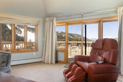 a living room with a chair and large windows at 2300 Red Hawk Lodge condo in Keystone