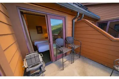 a small balcony with two chairs and a bedroom at Beautiful 3 Bedroom Mountain Condo In River Run Village With Hot Tub Access And Walking Distance To The Gondola in Keystone