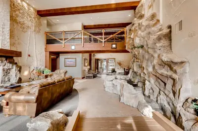 a large living room with a large stone wall at Beautiful 1 Bedroom Mountain Condo In River Run Village With Hot Tub Access And Walking Distance To The Gondola in Keystone