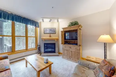 a living room with a couch and a tv and a fireplace at Charming Condo Nestled In The East Keystone Resort Neighborhood, Shuttle To Ski Slopes, Outdoor Pool And Hot Tub in Dillon