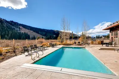 a swimming pool with chairs and a house at Red Hawk Townhomes 2 Bedroom Rental In River Run Village in Dillon