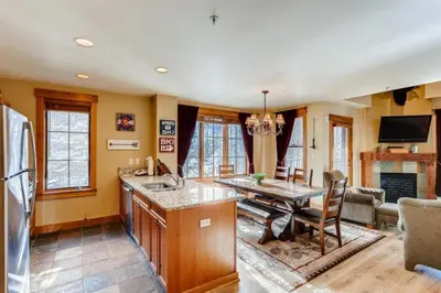 a kitchen and living room with a table and a refrigerator at Beautiful 2 Bedroom Mountain Condo In River Run Village With Hot Tub Access And Walking Distance To The Gondola in Keystone
