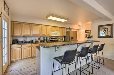 a kitchen with wooden cabinets and a bar with stools at Walk to Frisco Main St Townhome Steps to Trail! in Frisco