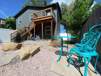 a patio with two blue chairs and a house at Spacious Downtown Apartment - Walk to Old Town FC! in Fort Collins