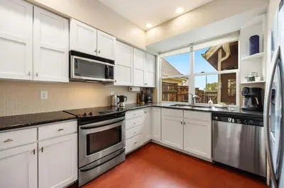 a kitchen with white cabinets and stainless steel appliances at Mid-century Mod Retreat near Old Town - Free Bikes in Fort Collins