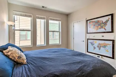 a bedroom with a large blue bed with windows at Rooftop Deck and City Views Denver Abode! in Denver