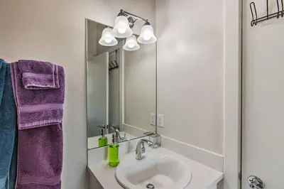 a bathroom with a sink and a mirror and purple towels at Rooftop Deck and City Views Denver Abode! in Denver