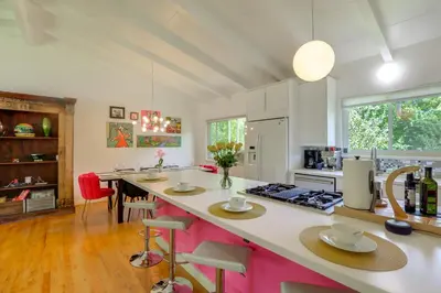 a kitchen with a large island with pink accents at The Modern Ridge House with Yard in Wheat Ridge in Wheat Ridge