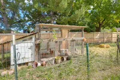 a cage with chickens in it in a field at The Modern Ridge House with Yard in Wheat Ridge in Wheat Ridge