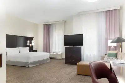 a hotel room with a bed and a flat screen tv at Staybridge Suites Denver - Central Park by IHG in Denver