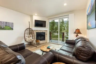 a living room with a leather couch and a fireplace at 202 Clearwater Lofts condo in Keystone