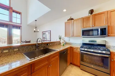 a kitchen with wooden cabinets and a stainless steel sink at Antlers Gulch #304 in Keystone