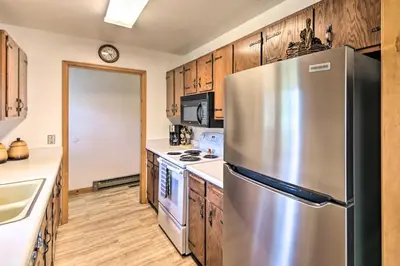 a kitchen with a stainless steel refrigerator and wooden cabinets at Rocky Mountain Breezes Cabin Grill and Deck! in Estes Park