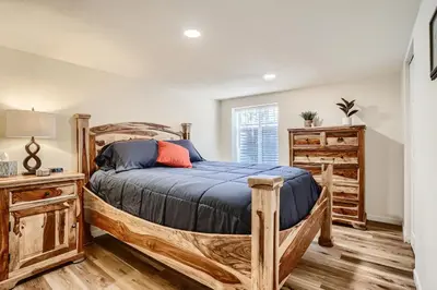 a bedroom with a wooden bed with a blue comforter at Sloans Lake Getaway - Basement Apartment Near Broncos and Downtown Denver in Lakewood