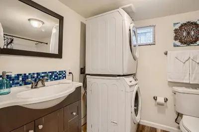 a bathroom with a sink and a washer and dryer at Sloans Lake Getaway - Basement Apartment Near Broncos and Downtown Denver in Lakewood
