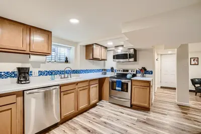 a kitchen with wooden cabinets and white counter tops at Sloans Lake Getaway - Basement Apartment Near Broncos and Downtown Denver in Lakewood